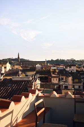 A rooftop terrace with a view of a cityscape, including buildings and a church spire. - Anchor Santa Croce (Firenze)