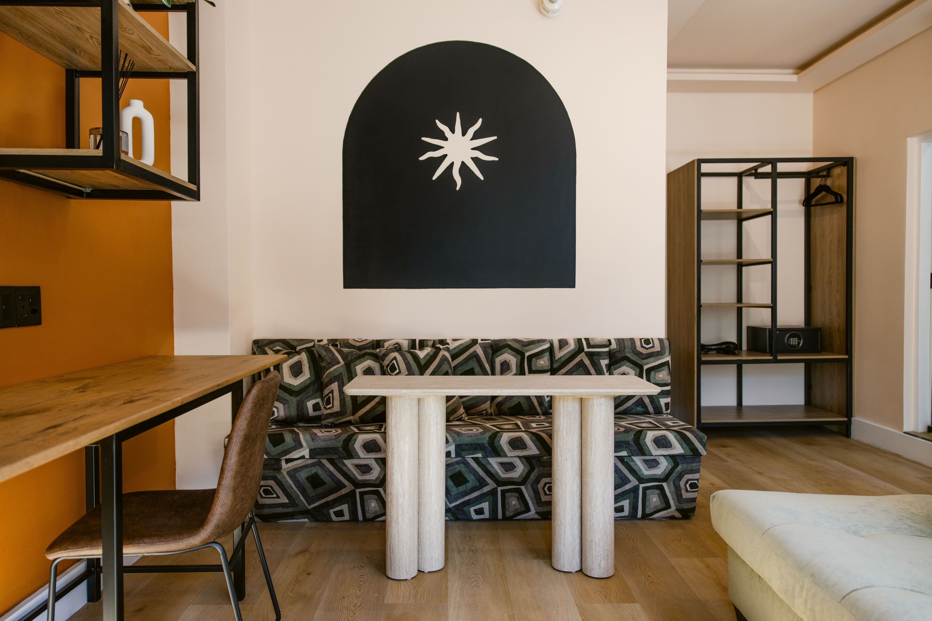 Uma sala de estar moderna com uma mesa de jantar de madeira, sofá estampado e uma parede preta com design de estrela branca.
