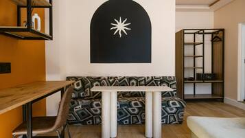 Uma sala de estar moderna com uma mesa de jantar de madeira, sofá estampado e uma parede preta com design de estrela branca.