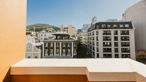 Vista de un paisaje urbano con edificios, incluyendo un edificio blanco destacado con balcón en primer plano.