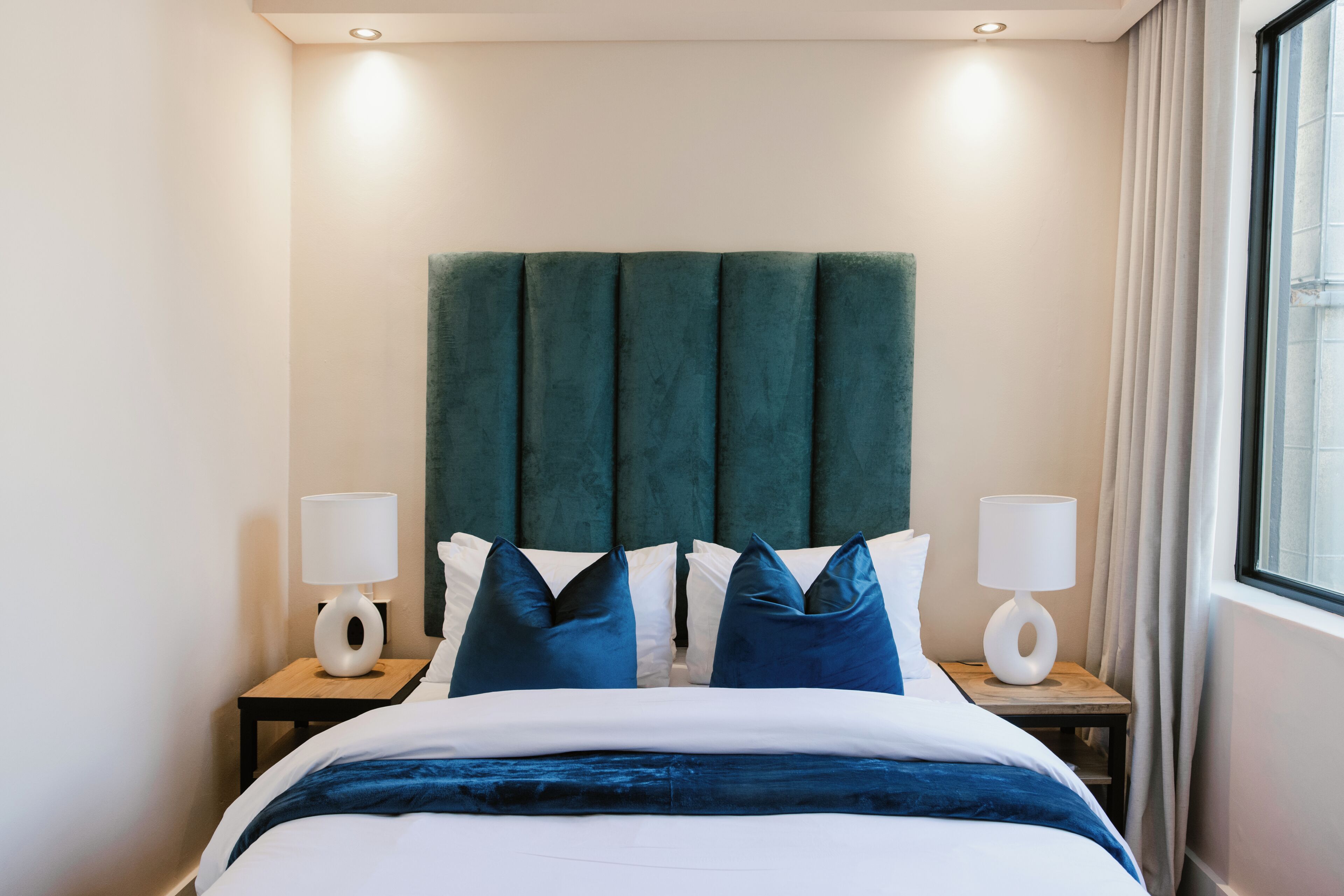 Ein Hotelzimmer mit einem Bett, zwei Nachttischen und einem fenster mit Vorh ängen.