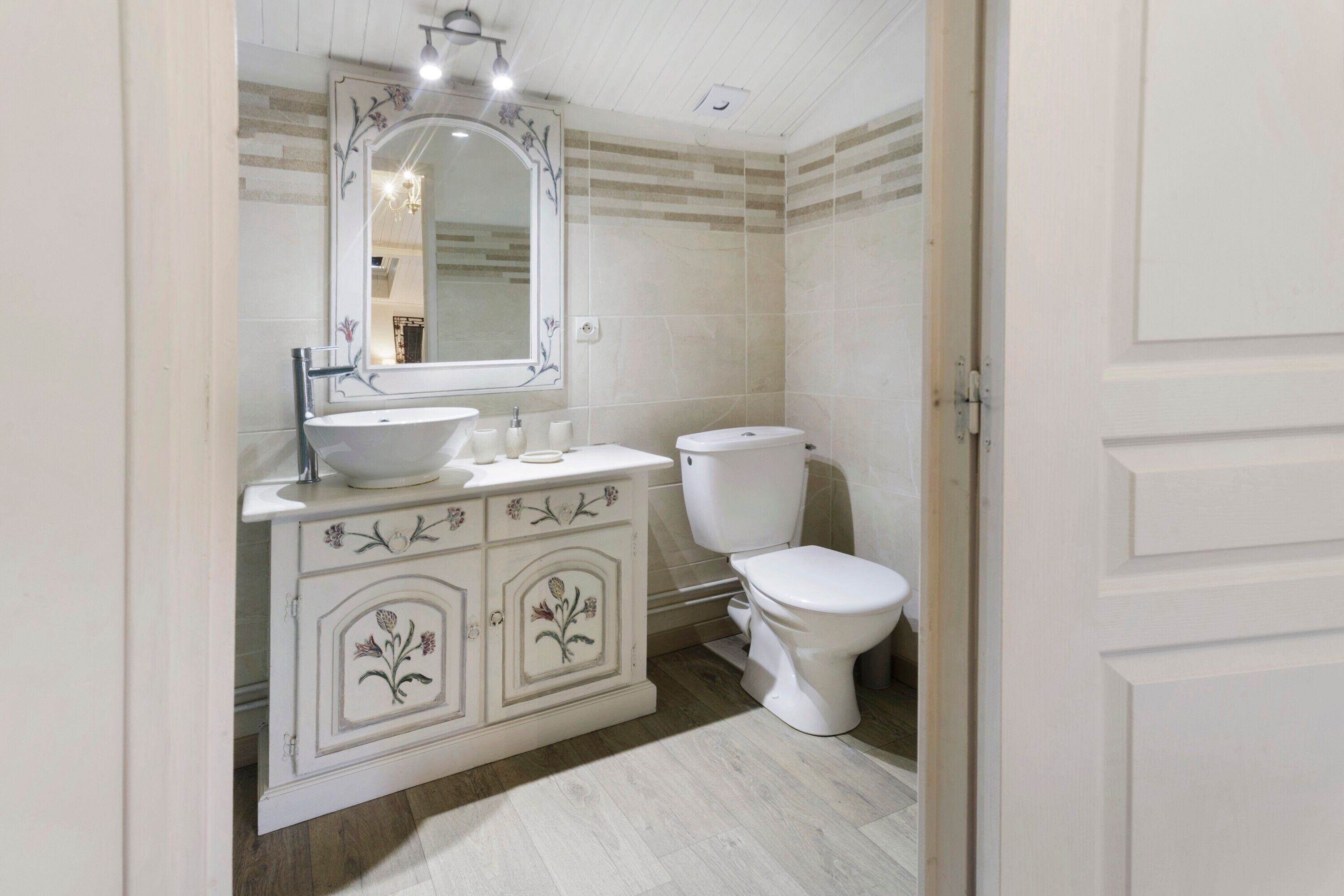 A bathroom with a white sink, mirror, and toilet.