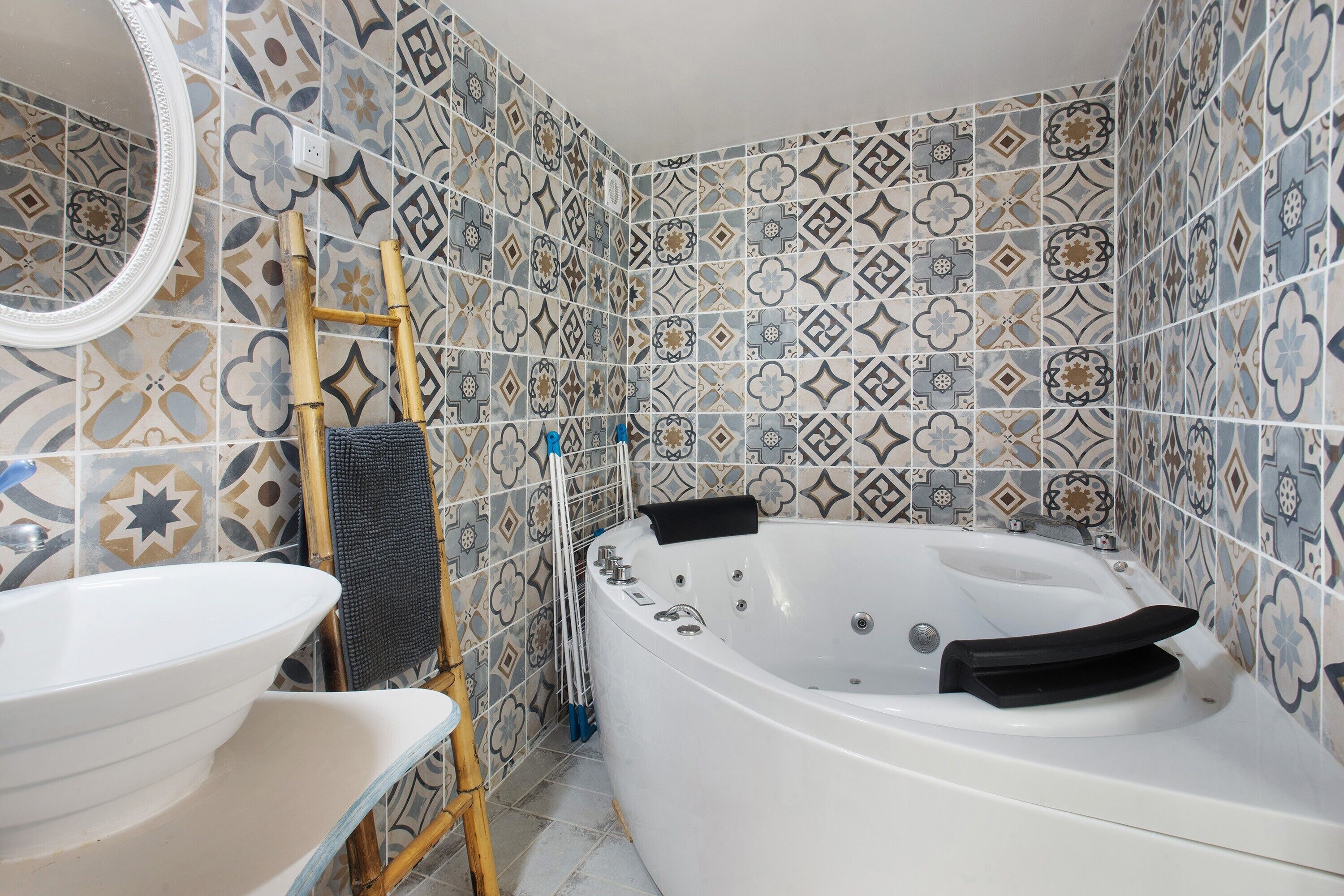 Une salle de bain avec une baignoire blanche, un lavabo blanc et des carreaux décoratifs sur les murs.