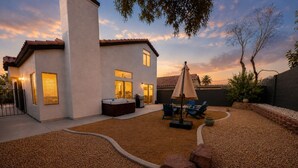 A modern house with a patio area, a hot tub, and outdoor seating. - Modern 3BR/3BA Retreat I Spa, BBQ, 15 Min to Strip (Las Vegas)