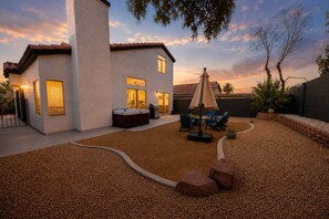 A modern house with a patio area, a hot tub, and outdoor seating. - Modern 3BR/3BA Retreat I Spa, BBQ, 15 Min to Strip (Las Vegas)