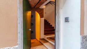 Una scala che conduce a un piano superiore, una porta verde e una presa elettrica a parete.