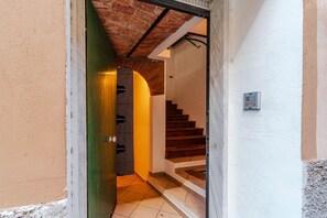 Una scala che conduce a un piano superiore, una porta verde e una presa elettrica a parete.