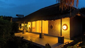 A thatched-roof building with large windows and a well-lit interior. - ELIVAAS Kimaya Suite With Game Zone (Gurugram)