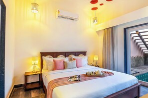 A hotel room with a bed, bedside lamps, a window with a view, and an air conditioning unit. - ELIVAAS Kimaya Suite With Game Zone (Gurugram)