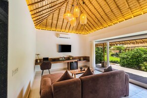 Un salon moderne doté d’un téléviseur à écran plat, d’un plafond en bois et d’une grande fenêtre donnant sur un jardin.
