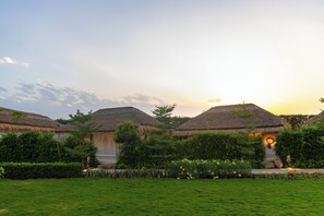 A thatched-roof building with a well-maintained garden in front. - ELIVAAS Kimaya Suite With Game Zone (Gurugram)