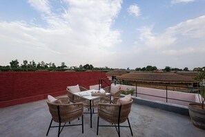 Une terrasse sur le toit, aménagée avec des meubles en osier, une table et un pot de fleurs.