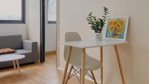 Ett modernt vardagsrum med en soffa, ett litet bord med en växt och en tavla, samt utsikt över staden genom ett fönster.