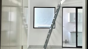 En modern inredning med en trappa, ett stort fönster och ett köksområde.