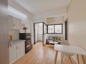 Een ruimtelijke woonkamer met kitchenette, eethoek en een bank.