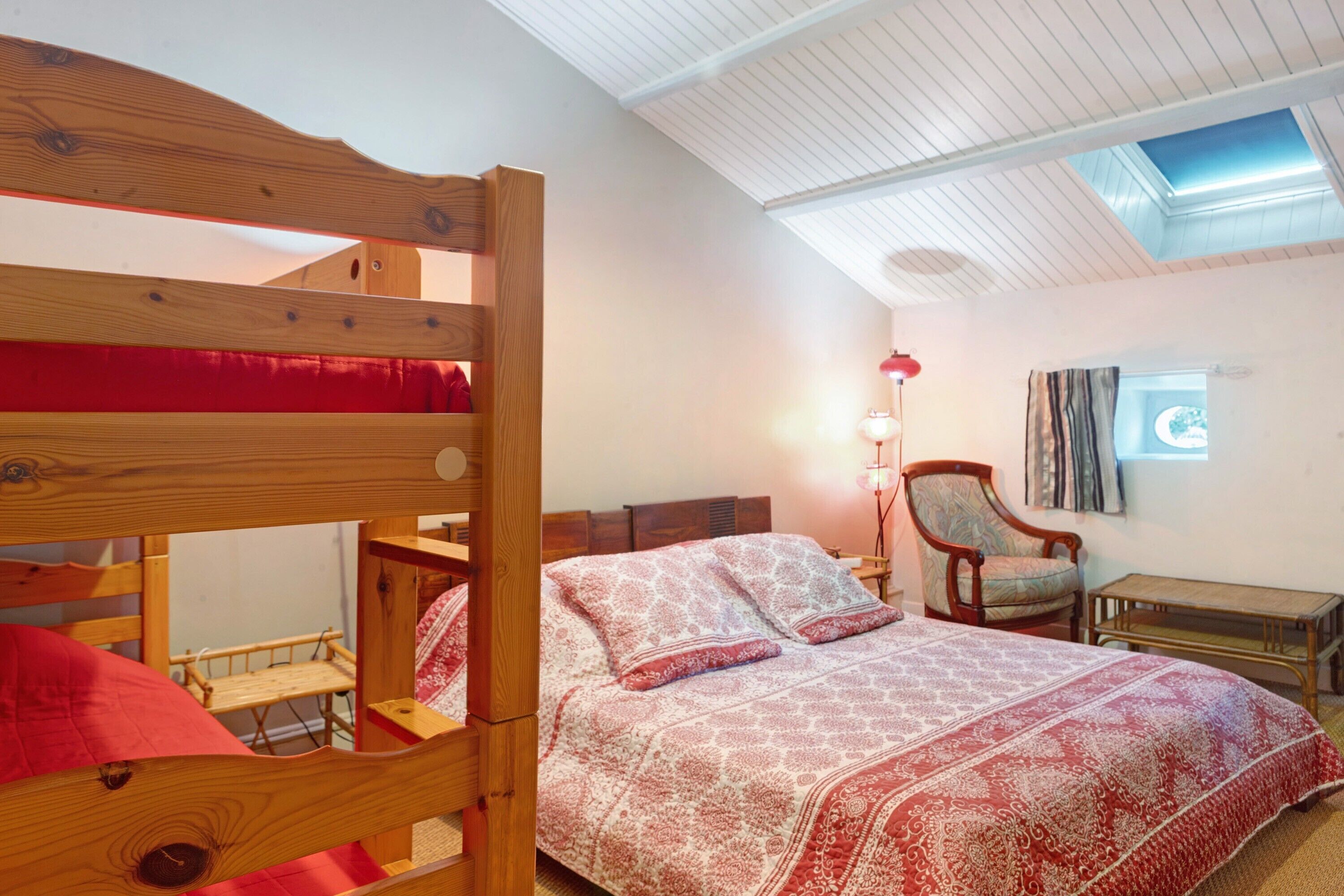 A room with a bunk bed, a desk, a chair, and a lamp.