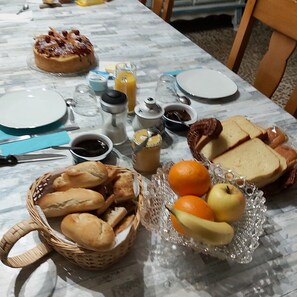 Aamiaispöytä, jossa on leipää, hedelmiä ja erilaisia lisukkeita.