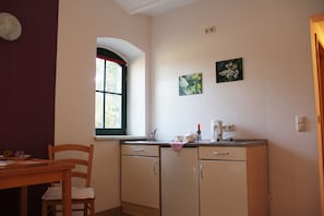 Eine kleine Küche mit Fenster, Spüle und Arbeitsplatte mit Küchenutensilien.
