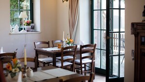 Uma sala de jantar com mesa posta para quatro pessoas, janela com vista e porta que dá para o exterior.