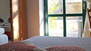 Quarto com cama, janela com cortinas e vista para o exterior.