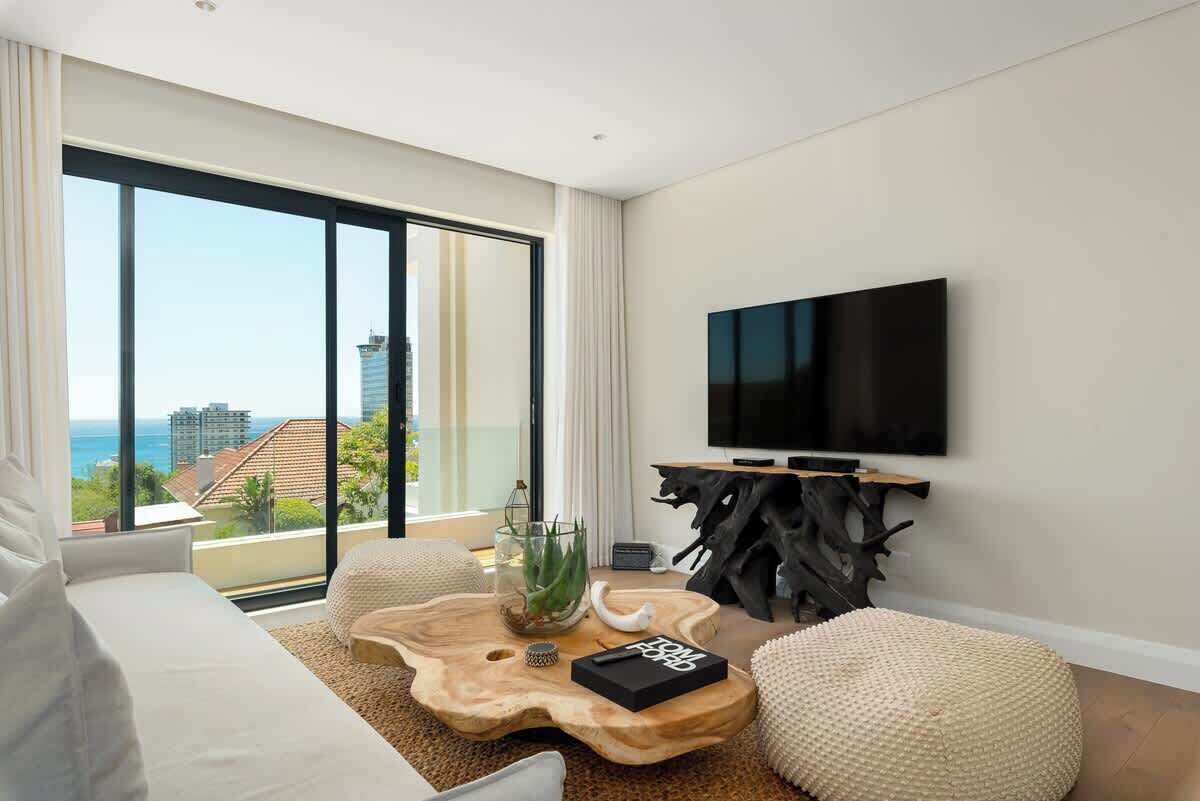 A modern living room with a large window, a flat-screen TV, a wooden coffee table, and a sofa.