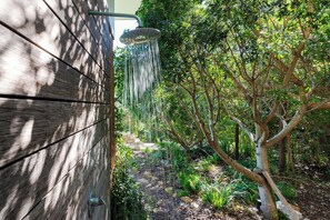 A wooden wall with a showerhead, surrounded by lush greenery and trees. - Golden View Villa | The Ultimate Sunset Escape (Cape Town)