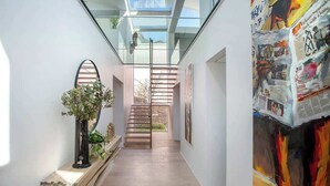 Ein modernes Interieur mit Glasdecke, einer Holztreppe und einer Wand mit abstrakter Kunst.