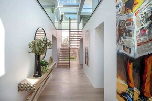 Ein modernes Interieur mit Glasdecke, einer Holztreppe und einer Wand mit abstrakter Kunst.