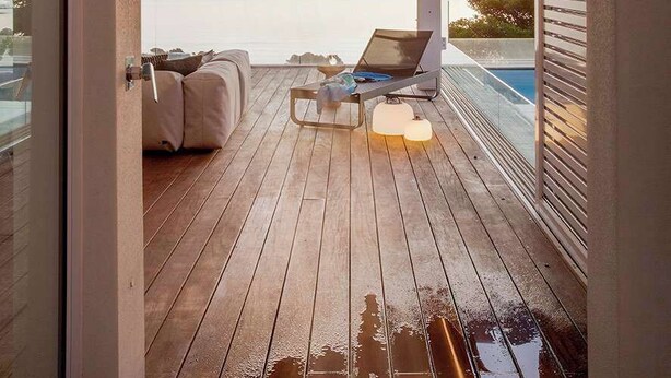Eine Holzterrasse mit Blick auf das Meer, ein Laptop und ein Liegestuhl.