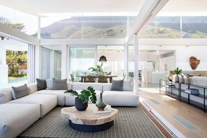 Ein modernes Wohnzimmer mit einer Eckcouch, einem runden Couchtisch und Blick ins Freie.