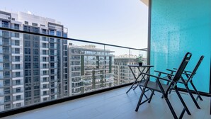 A balcony with a view of high-rise buildings, a table, and two chairs. - Sophisticated Studio Escape in JVC  (Dubai)