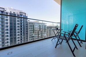 Ein Balkon mit Blick auf hohe Gebäude, einem Tisch und zwei Stühlen.