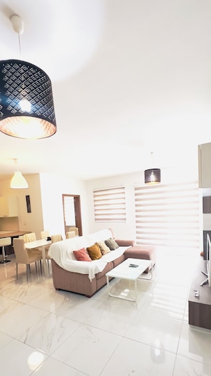 Uma sala de estar moderna com sofá, mesa de centro e área de jantar.