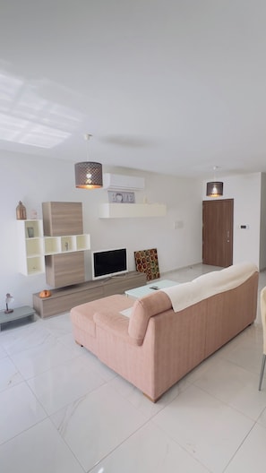 Una sala de estar moderna con sofá, televisor y elementos decorativos.