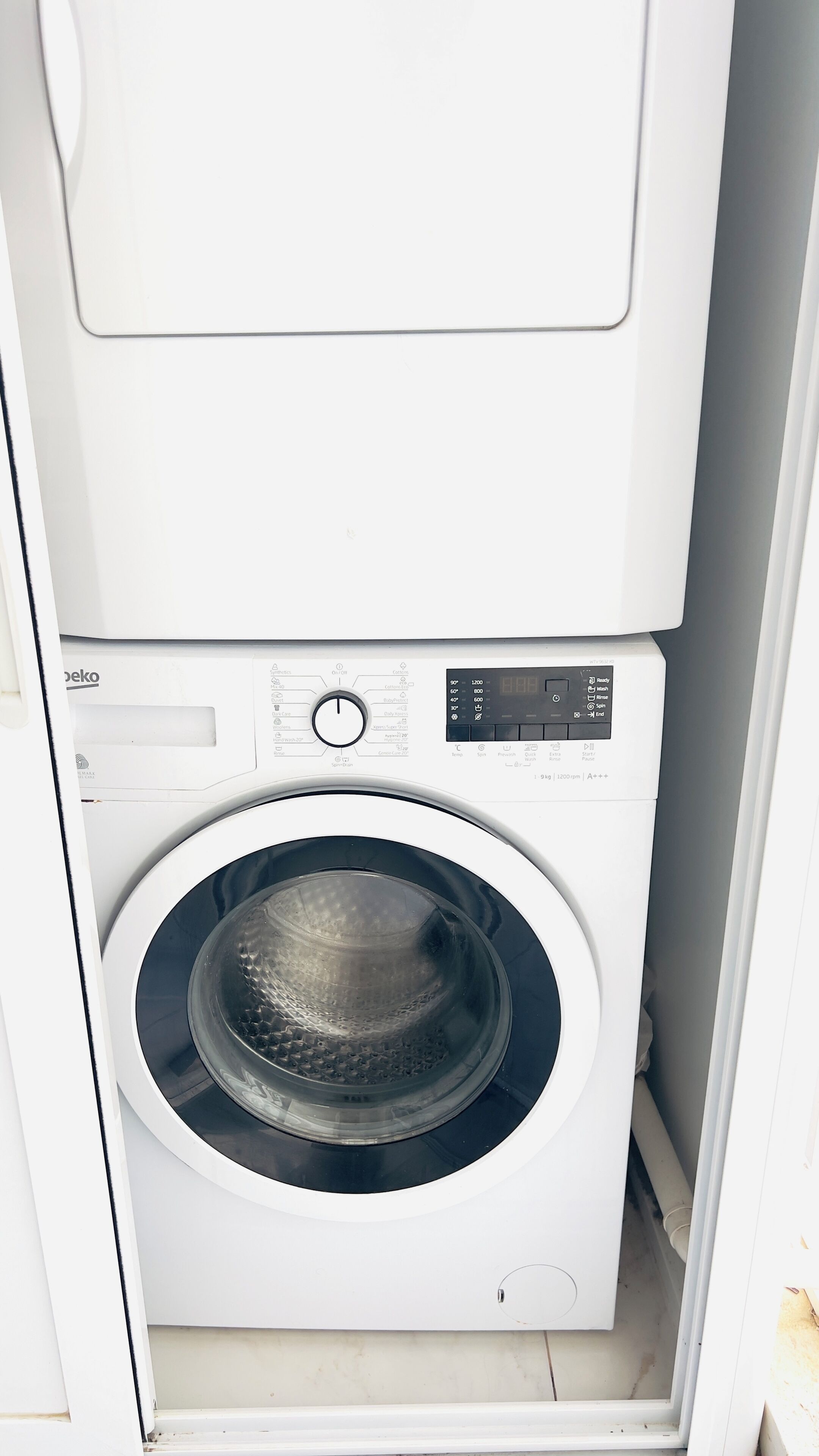 A front-loading washing machine with a digital display, control panel, and a transparent door.