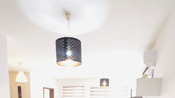 Amplia sala de estar con sofá, mesa de comedor y una lámpara colgante moderna.