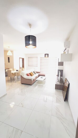 A spacious living area with a sofa, dining table, and a modern pendant light. - 8 Delphi Court (San Pawl il-Baħar)