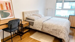 Ein Schlafzimmer mit Bett, Schreibtisch, Stuhl und Fenster.