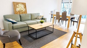 Ein modernes Wohnzimmer mit Sofa, Couchtisch und Essbereich.