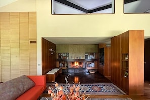 Una sala de estar moderna con chimenea, estanterías y un sofá rojo.