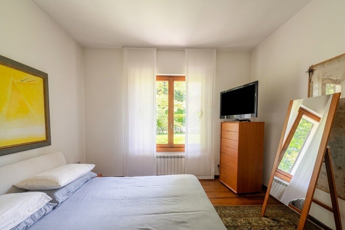 Ein Schlafzimmer mit Bett, Kommode, Fernseher und einem Bild an der Wand.