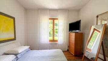 Ein Schlafzimmer mit Bett, Kommode, Fernseher und einem Bild an der Wand.