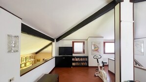 A room with a staircase, a treadmill, a television, and a bookshelf.