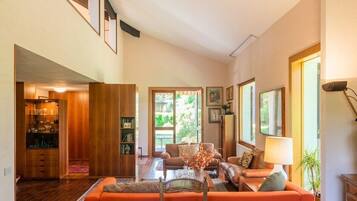 Un salon spacieux avec un canapé, des fauteuils et une table basse. On y trouve également une bibliothèque et un coin repas avec une table.