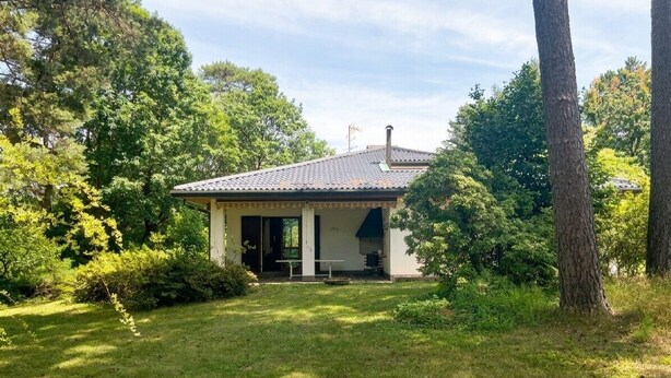 Een gelijkvloers huis met pannendak, overdekt terras en gazon.