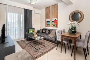 A modern living room with a sofa, coffee table, and dining table.