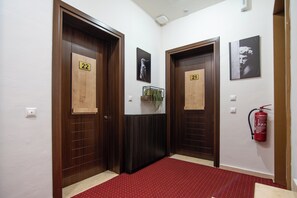 Un pasillo con dos puertas indicadas con los números 21 y 22, un extintor y una alfombra roja.