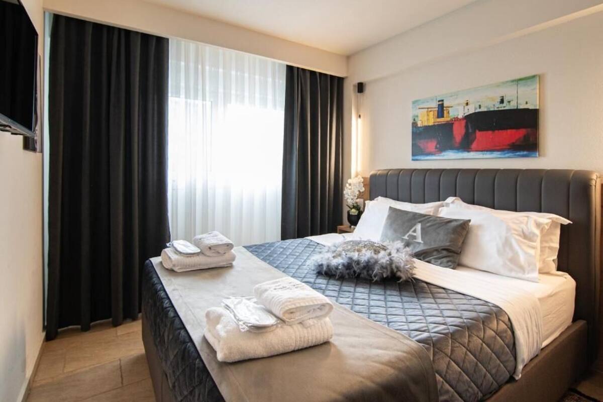 Une chambre d’hôtel avec un lit, un tableau au mur et une fenêtre avec des rideaux.