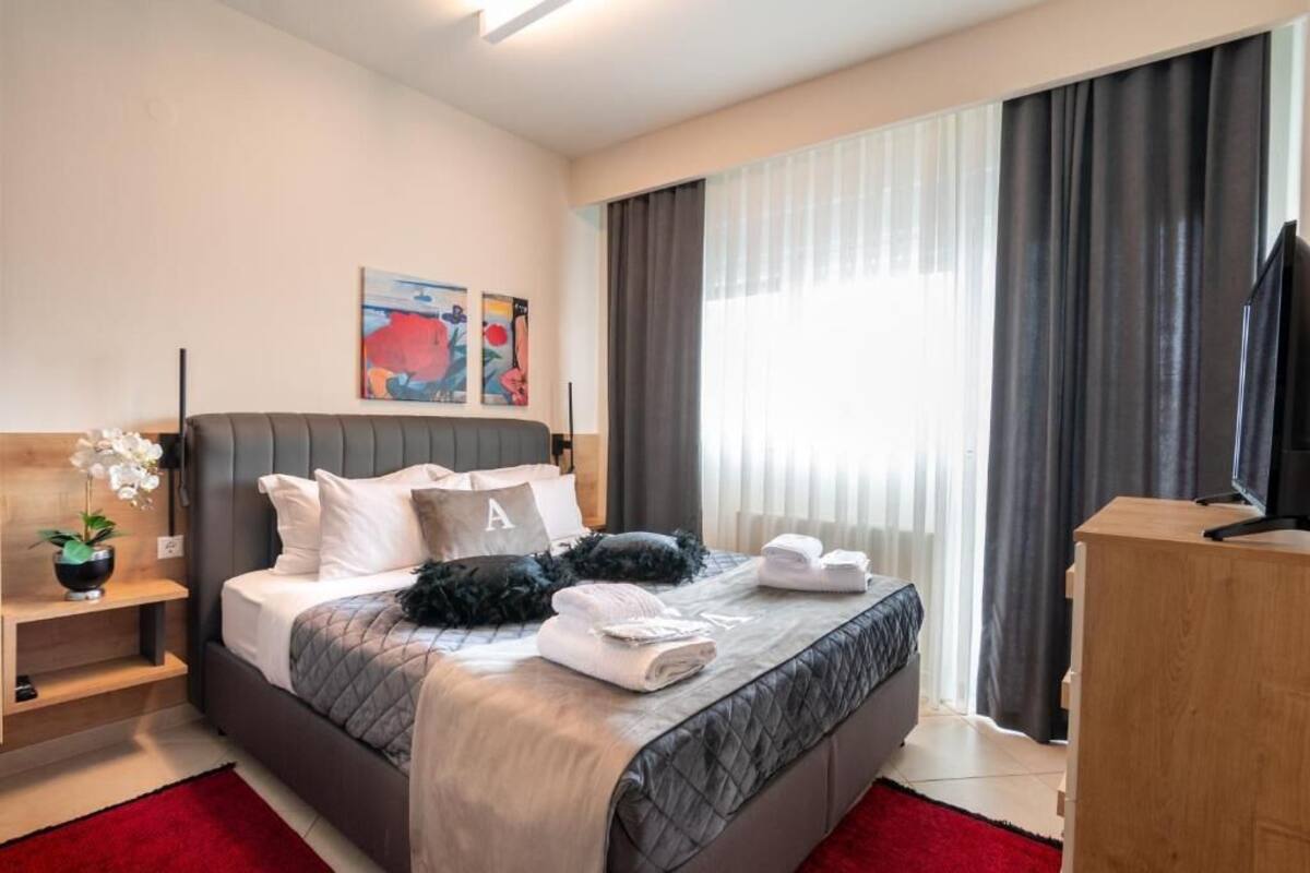 Une chambre d’hôtel moderne équipée d’un lit, d’une télévision, d’un bureau et ornée d’œuvres d’art au mur.