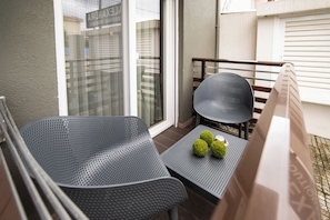 A balcony with two metal chairs, a small table, and a potted plant. - Alexandra Boutique Residence Seaside  (ALEXANDROUPOLIS)